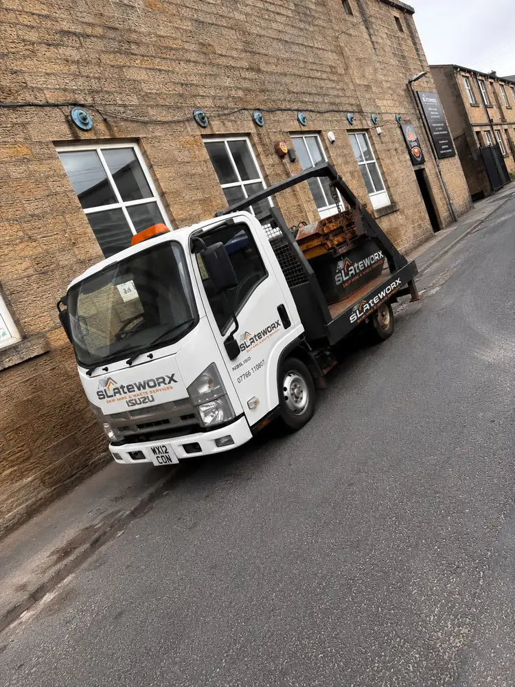 White Slate Worx Isuzu skip truck outside the Colne roofing supplies yard